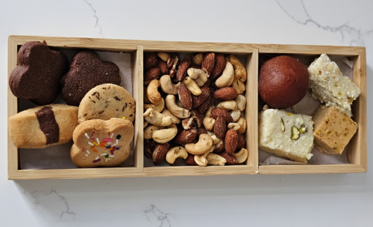 Wooden snack box with cookies, nuts, and other treats on a marble surface