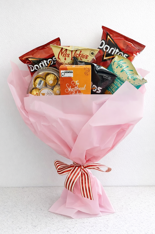 Bouquet of snacks and candies wrapped in pink paper with a bow on a white background